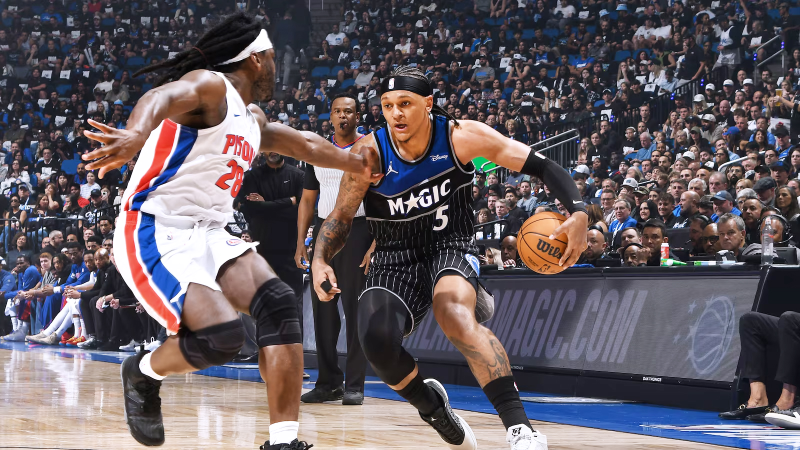 Paolo Banchero is guarded by a Detroit Pistons player on the court at Kia Center.